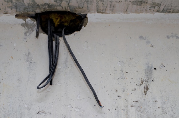 Naprawa w mieszkaniu Przewody wystają z dziury w betonowej ścianie Właściciel domu czeka na elektryka