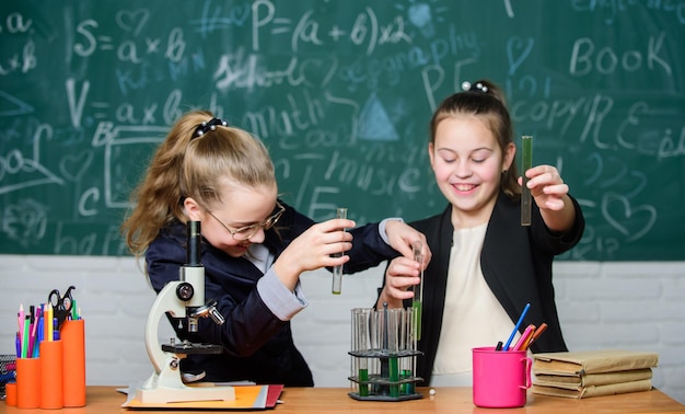 Naprawdę zajęty Dziewczynki w szkolnym laboratorium Nauka to przyszłość Małe dziewczynki naukowiec pracują z mikroskopem Badania chemiczne Biologia Nauka Szczęśliwe dziewczynki eksperymenty naukowe w laboratorium