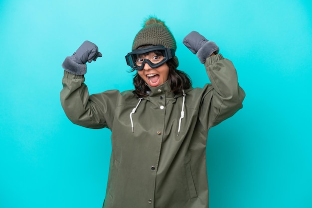 Narciarz latynoska kobieta w okularach snowboardowych na niebieskim tle