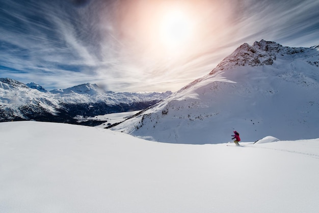 Narciarz na nartach zjazdowych w wysokich górach przed zachodem słońca
