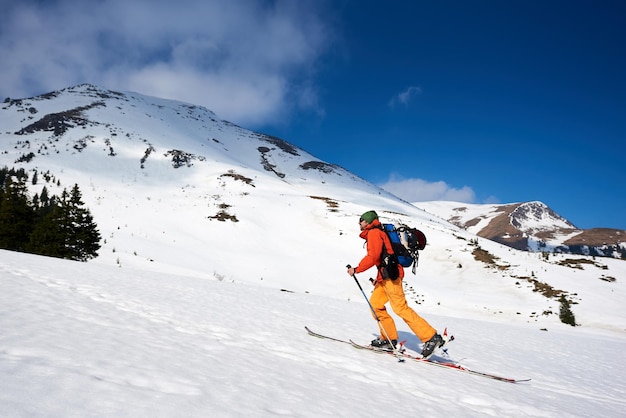 Narciarz turysta z plecakiem na tle błękitnego nieba i pięknej górskiej panoramy