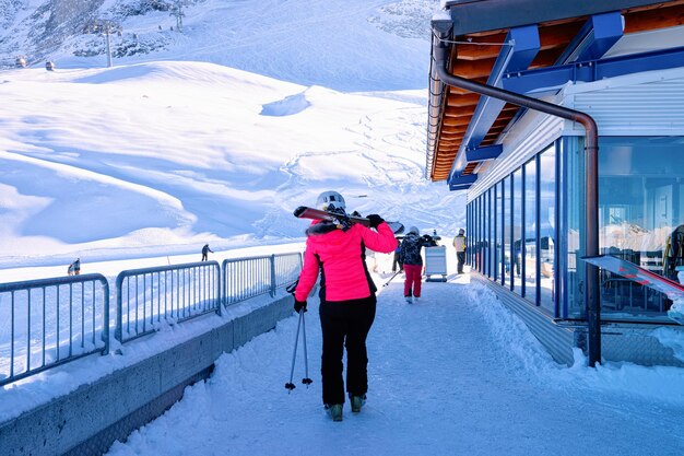 Narciarz Z Nartami Do Stacji Kolejki Linowej Na Lodowcu Hintertux W Tyrolu W Mayrhofen W Austrii, Alpy Zimą. Lady Girl W Budynku Biletowym W Hintertuxer Gletscher W Górach Alpejskich