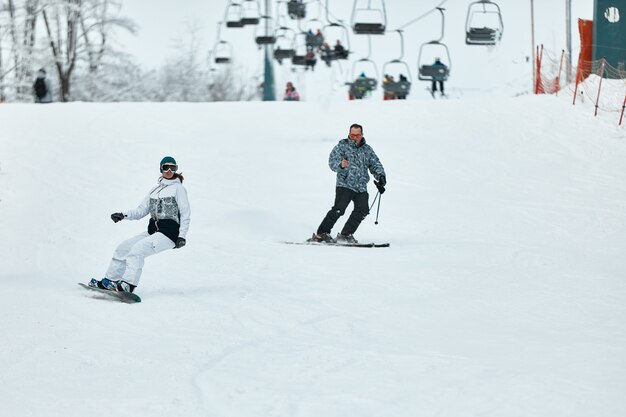 Narciarz zjazdowy. Snowboardziści i narciarze jeżdżą po śniegu w górach. Zjazd. Sezon dla narciarzy przygodowych. Ośrodki narciarskie i snowboardowe. Sprzęt narciarski i snowboardowy. Miłośnicy sportów zimowych.