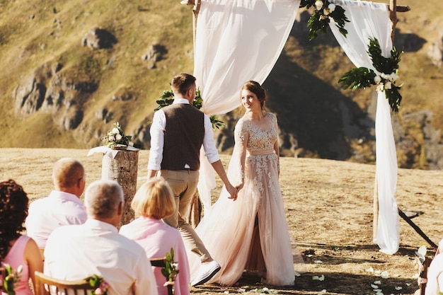 Zdjęcie narzeczeni wyglądają pięknie podczas ceremonii ślubnej na szczycie góry gdzieś w gruzji
