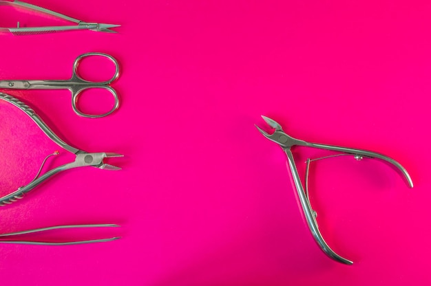 Narzędzia do manicure i pedicure na różowym tle Nożyczki do pilników pęseta szczypce Narzędzia medyczne widok z góry