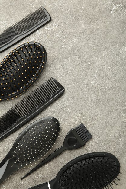 Narzędzia do włosów, koncepcja piękna i fryzjerstwa - różne szczotki lub grzebienie na szarej powierzchni
