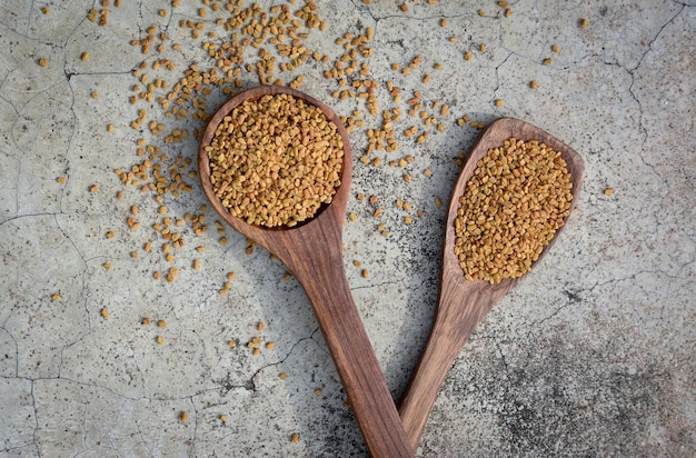 Zdjęcie nasiona fenugreku w drewnianej łyżce na teksturowanym tle