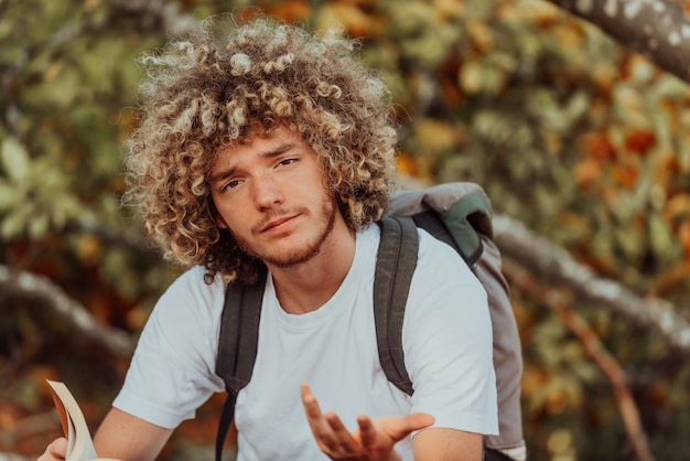 Nastolatek afro relaksuje się czytając książkę siedząc w lesie przy pięknej jesiennej pogodzie