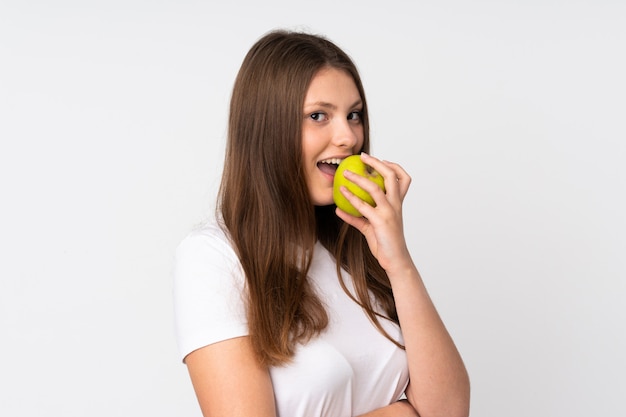 Nastolatek caucasian dziewczyna odizolowywająca na biel ścianie je jabłka