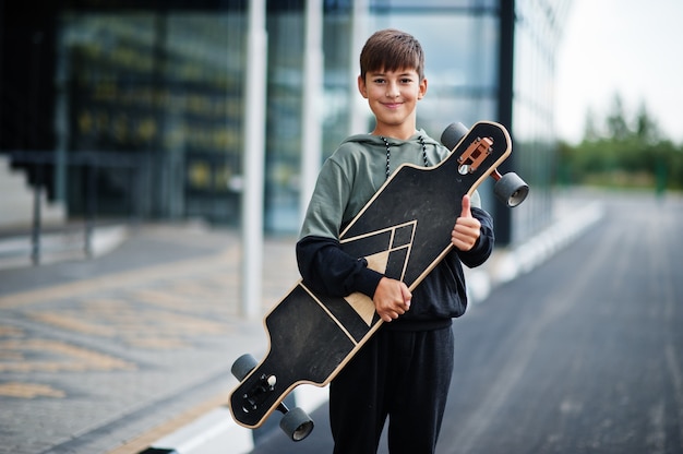 Nastolatek chłopiec w sportowym garniturze z longboardem.