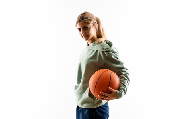 Nastolatek dziewczyna bawić się koszykówkę nad odosobnioną biel ścianą