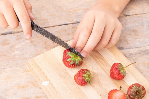 nastolatek krojenia truskawek na pokładzie kuchni, aby zrobić kulki smoothie, metalowy nóż