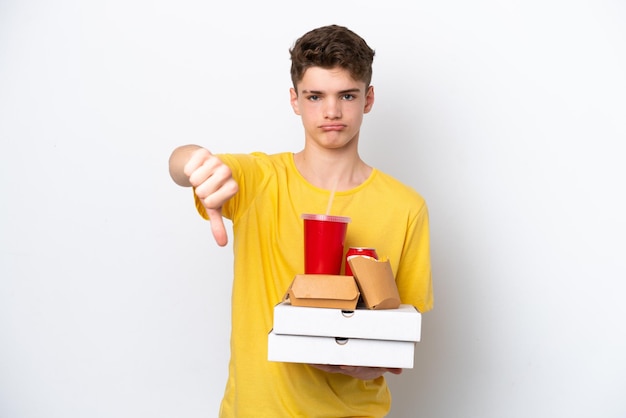 Nastolatek Rosjanin Trzymający Fast Food Na Białym Tle Pokazując Kciuk W Dół Z Negatywnym Wyrażeniem