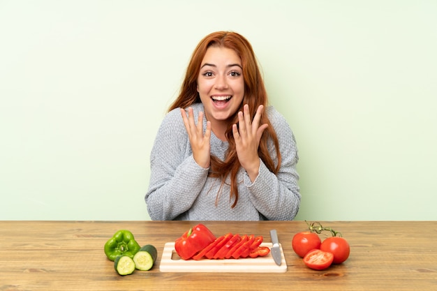 Nastolatek rude dziewczyny z warzywami w tabeli z niespodzianką wyraz twarzy