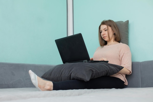 Nastolatek siedzący na łóżku przed laptopem z zamiarem nauczenia się żyć w Internecie