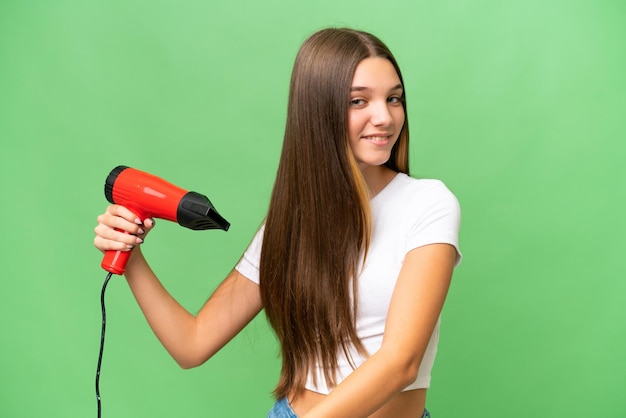 Nastolatka Kaukaska dziewczyna trzyma suszarkę do włosów nad odosobnionym tłem