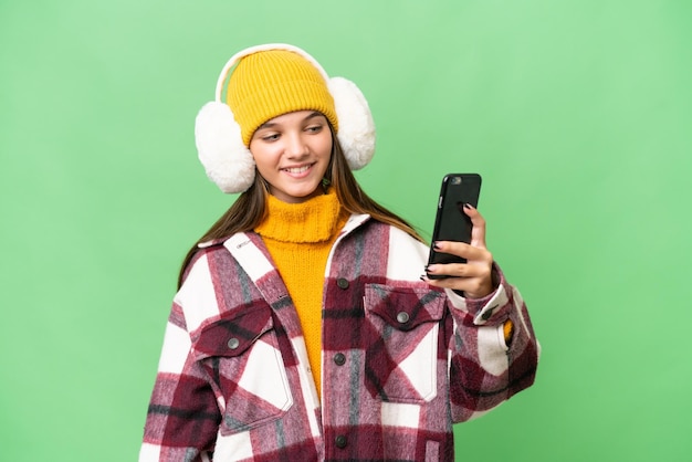 Nastolatka kaukaska dziewczyna ubrana w zimowe mufki na odosobnionym tle, robiąca selfie