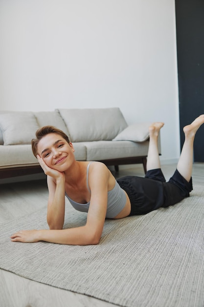 Nastolatka leżąca na podłodze w domu uśmiechająca się w domowych ubraniach z krótką fryzurą bez filtrów wolna przestrzeń do kopiowania