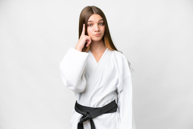 Nastolatka robi karate na białym tle myśląc o pomyśle