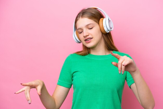 Nastolatka rosyjska dziewczyna na różowym tle słucha muzyki i tańczy