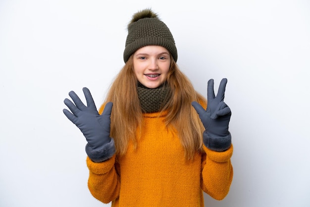 Nastolatka rosyjska dziewczyna ubrana w zimową kurtkę na białym tle, licząc osiem palcami