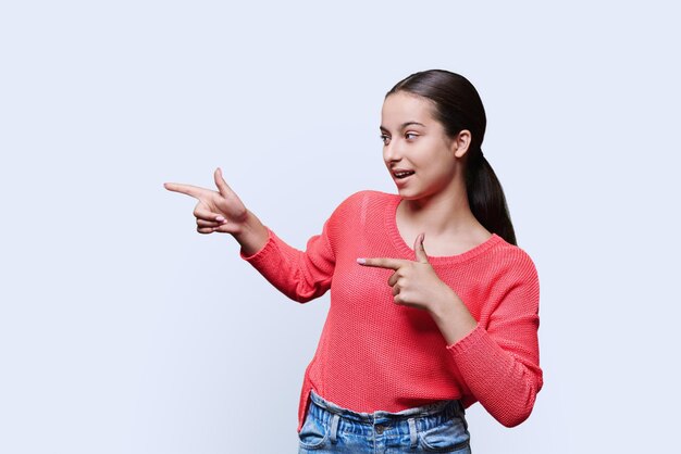 Nastolatka studentka wskazująca ręką na puste miejsce na tekst na białym tle