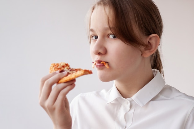 Nastolatka W Białej Koszuli Odgryzła Kawałek Pizzy I Trzyma Ją W Ustach.