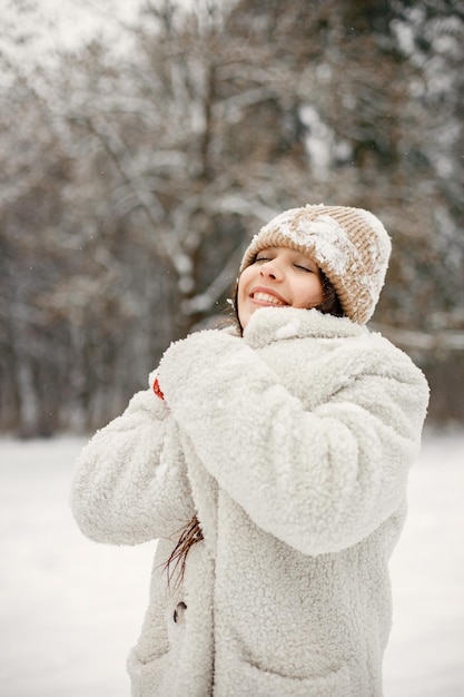 Nastolatka w czerwonych rękawiczkach stoi w winter park i pozuje do zdjęcia