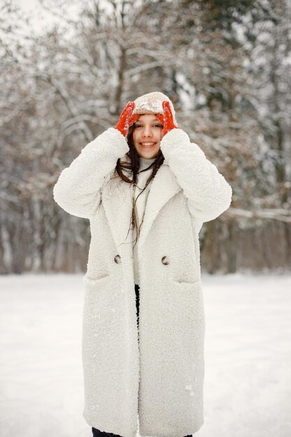 Nastolatka w czerwonych rękawiczkach stoi w winter park i pozuje do zdjęcia