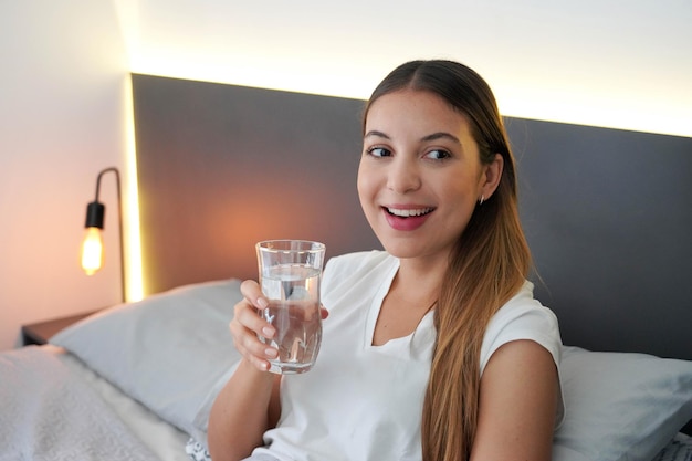 Zdjęcie nastolatka w łóżku pije szklankę wody po prostu obudził się rano