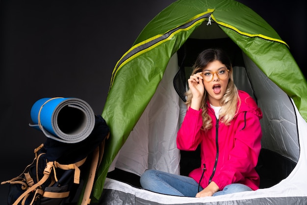 Nastolatka wewnątrz zielonego namiotu kempingowego