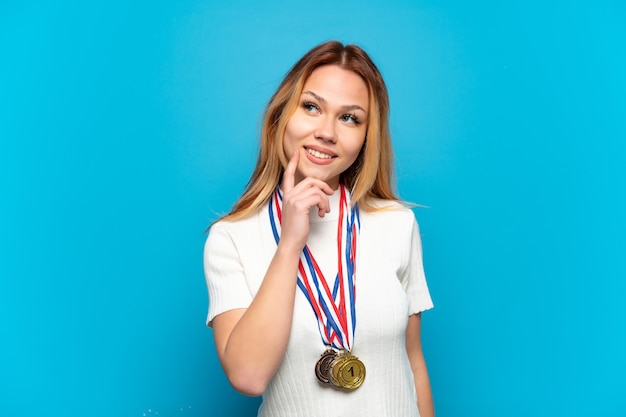 Zdjęcie nastolatka z medalami na białym tle myśli o pomyśle, patrząc w górę