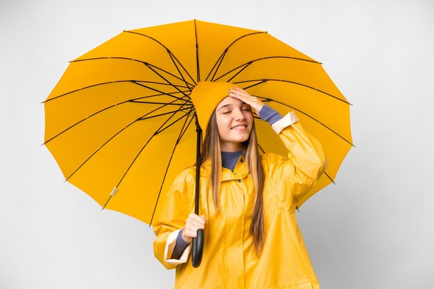 Nastolatka z płaszczem przeciwdeszczowym i parasolem na białym tle uśmiecha się dużo