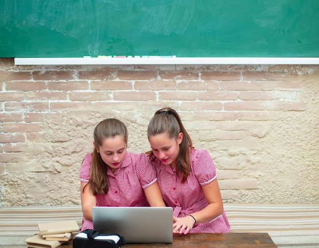 Nastolatki młode uczennice z laptopem na tablicy w szkole. Portret nastolatki studentki.