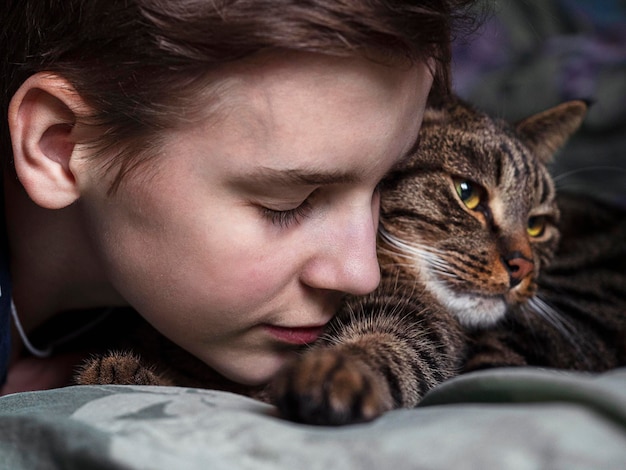 Nastoletni chłopak przytulający pasiastego kota
