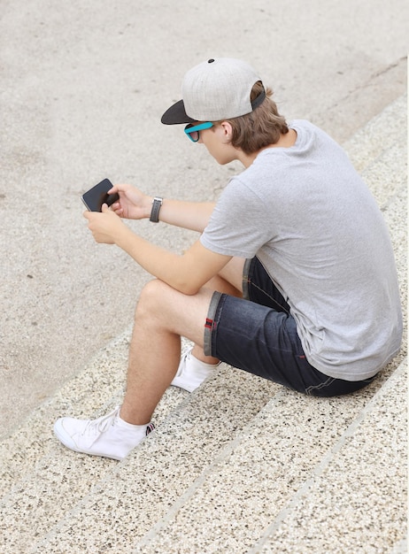 Nastoletni chłopak wpisuje wiadomość tekstową za pomocą smartfona