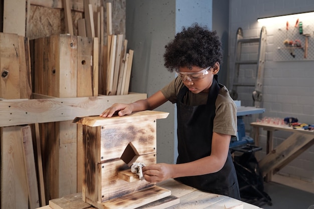 Nastoletni chłopiec buduje ptaszarnię w warsztacie