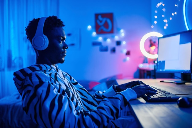 Nastoletni chłopiec grający w grę wideo na komputerze