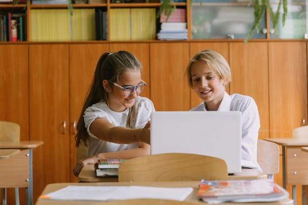 Nastoletni studenci pracujący razem przy użyciu laptopa w klasie