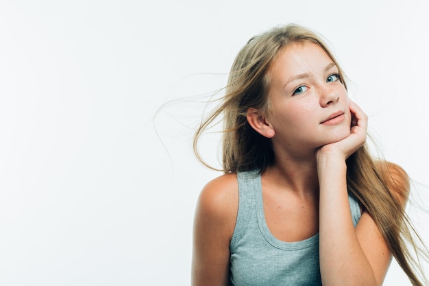 Nastoletnia dziewczyna dotyka jej policzka. Portret młodej kobiety z piegowatą twarzą. Na białym tle. Strzał studio.