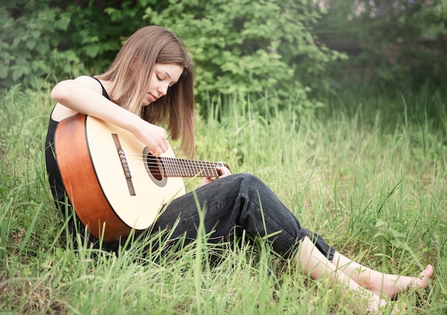 Zdjęcie nastoletnia dziewczyna gra na gitarze w parku