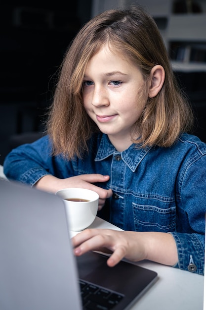 Nastoletnia dziewczyna siedzi przed laptopem, ucząc się online