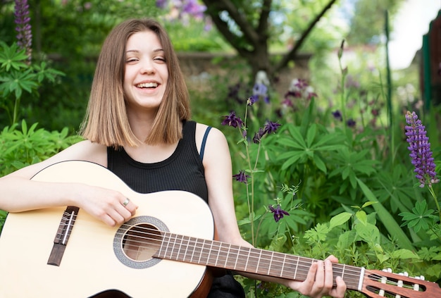 Nastoletnia dziewczyna siedzi z gitarą