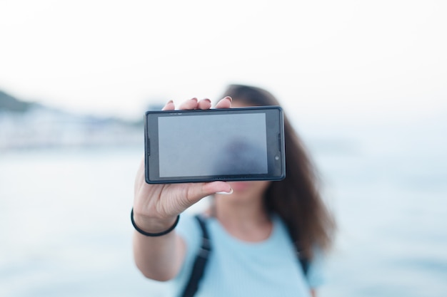 Nastoletnia dziewczyna stojąca na letniej, piaszczystej plaży przy selfie