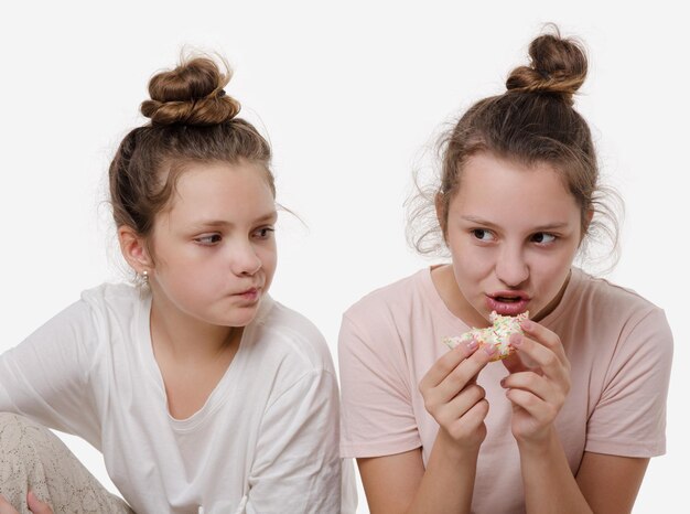 Nastoletnia dziewczyna trzyma w dłoni słodki kremowy tort i chce zjeść białe tło