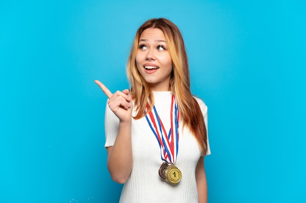 Nastoletnia Dziewczyna Z Medalami Na Białym Tle, Która Zamierza Zrealizować Rozwiązanie, Podnosząc Palec W Górę