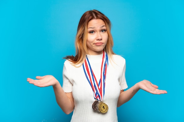 Zdjęcie nastoletnia dziewczyna z medalami na białym tle ma wątpliwości podczas podnoszenia rąk