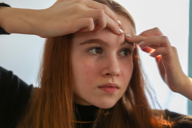 Nastoletnia dziewczyna z problemem trądziku ściska pryszcz w pomieszczeniu