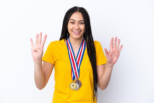 Nastoletnia dziewczyna z warkoczami i medalami na różowym tle, licząc dziewięć palcami