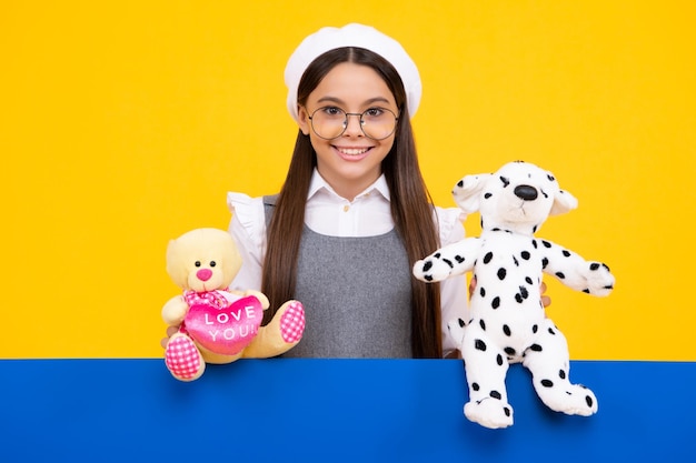 Zdjęcie nastoletnia dziewczynka dziecko w stroju codziennym trzymająca pluszową zabawkę na żółtym tle szczęśliwe dzieciństwo szczęśliwa twarz pozytywne i uśmiechnięte emocje nastolatka